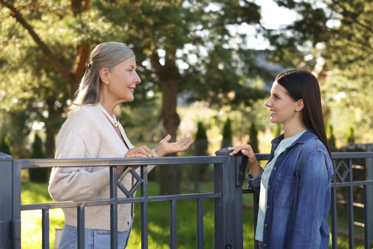 Happy women talking near fence outdoors